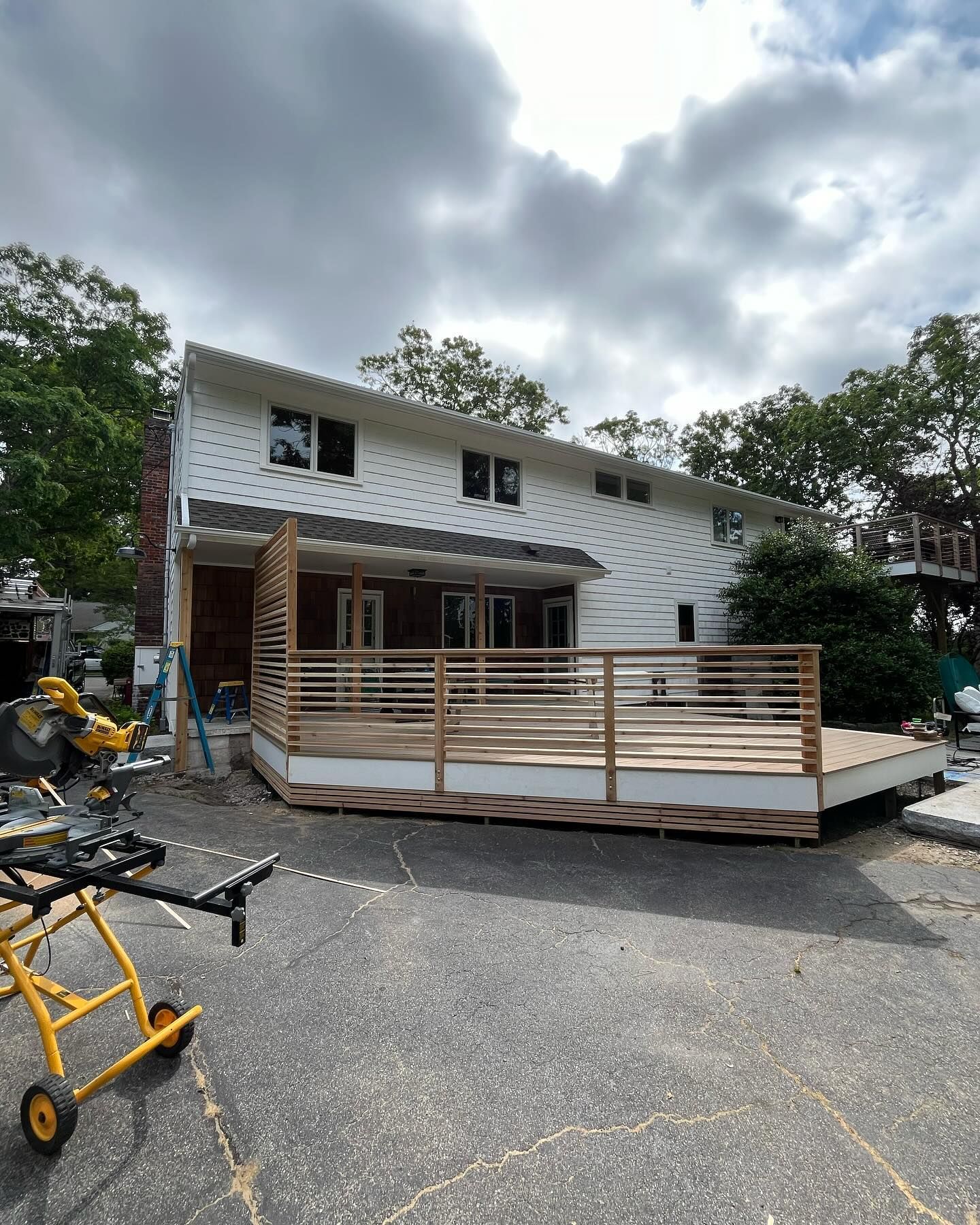 White storefront with wooden deck and railing in a gravel lot under cloudy skies