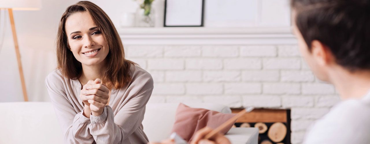 A woman is sitting on a couch talking to a therapist.