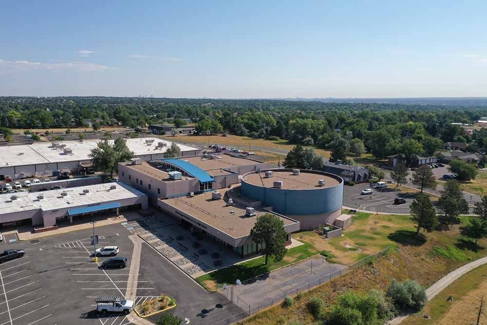 An aerial view of a large building with a parking lot in front of it.