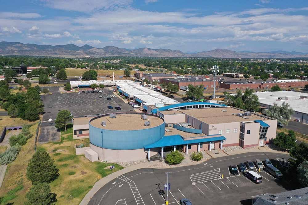An aerial view of a large building with a parking lot in front of it.
