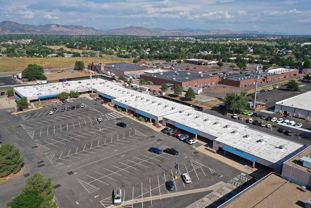 An aerial view of a shopping center with a lot of cars parked in front of it.