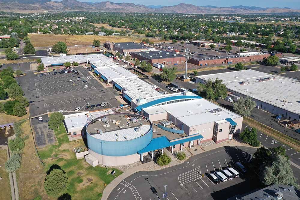 An aerial view of a large building in a city with mountains in the background.
