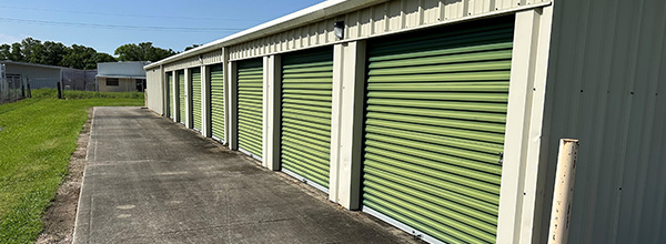 A row of storage units with green doors on a sunny day.