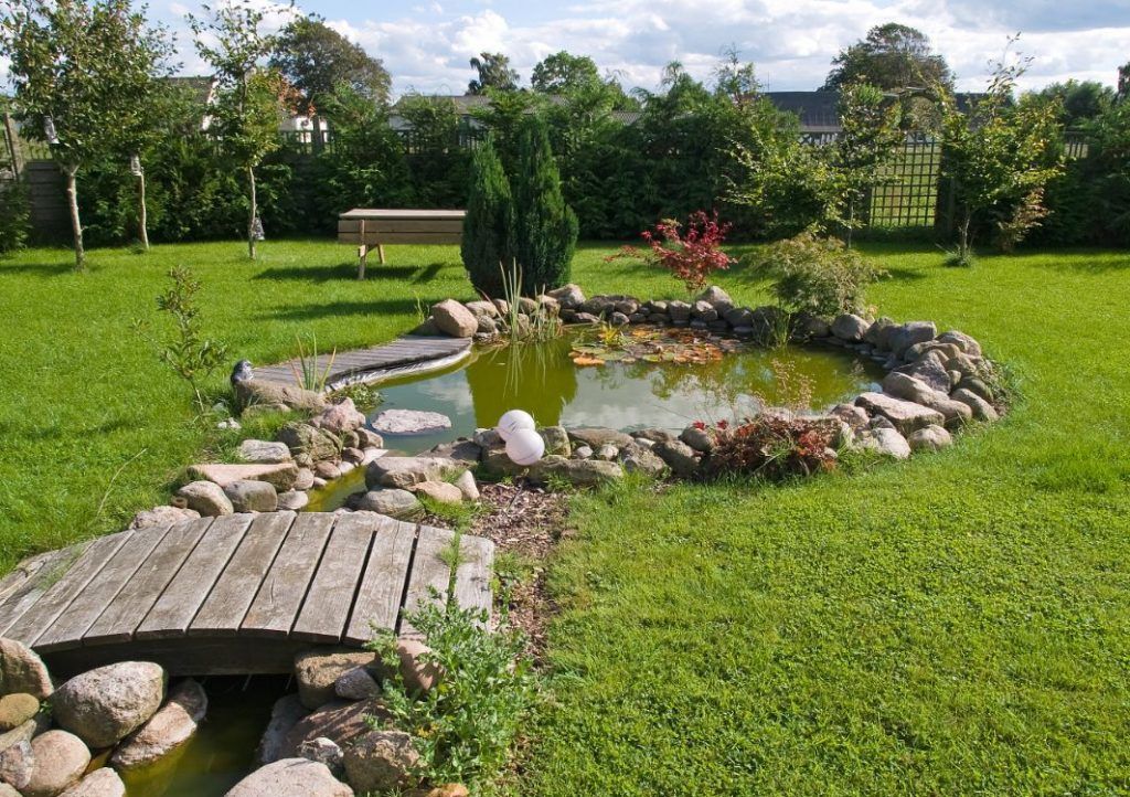 Circular backyard pond design with bridge
