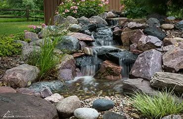 A waterfall is surrounded by rocks in a garden.