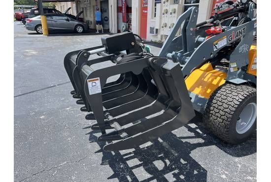 A red Toro Dingo compact track loader with fork attachments parked on asphalt.