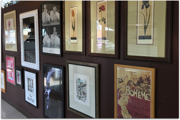 A wall of framed pictures including one that says boheme