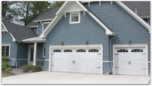 A blue house with white garage doors and a gray roof