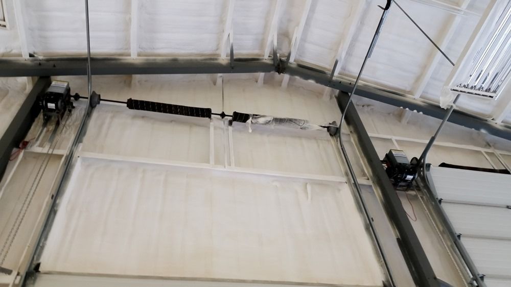 White interior view of a large industrial building with a garage door and overhead spring system.
