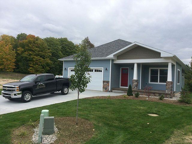 A truck is parked in front of a blue house.
