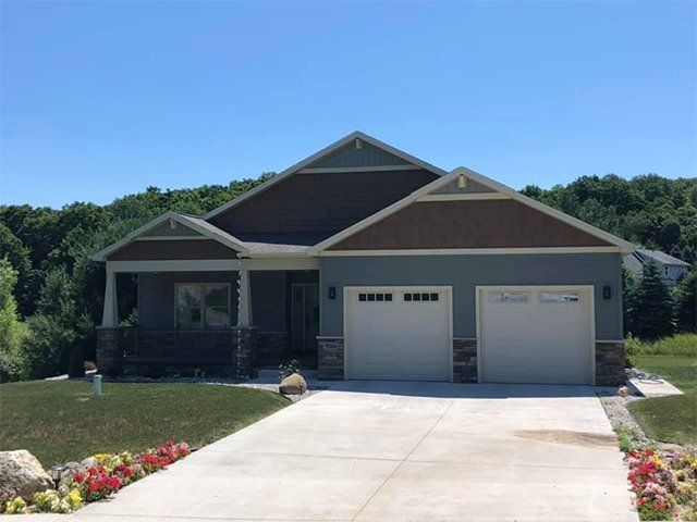 A house with two garage doors and a driveway in front of it.