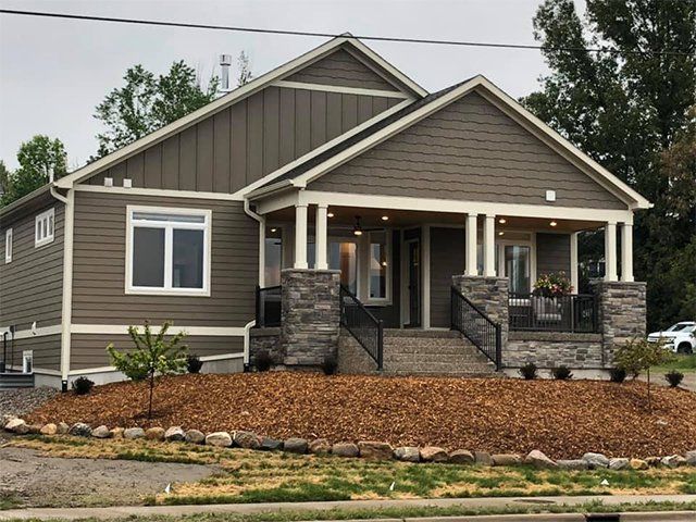 A large house with a porch and stairs on a hill