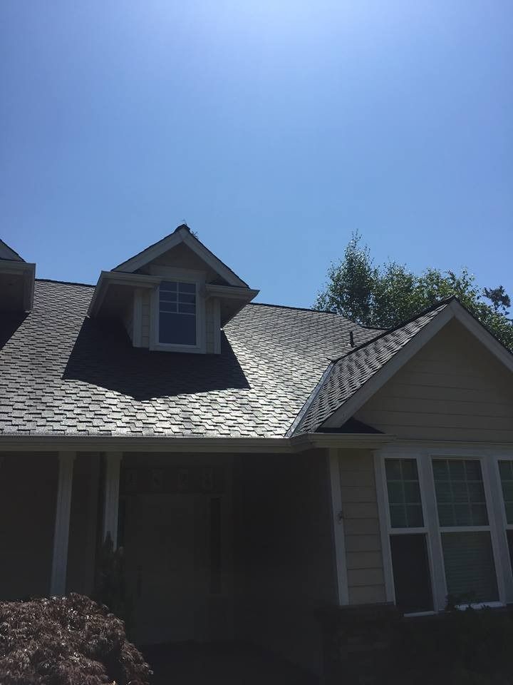 House exterior with gray roof and dormer under a clear blue sky