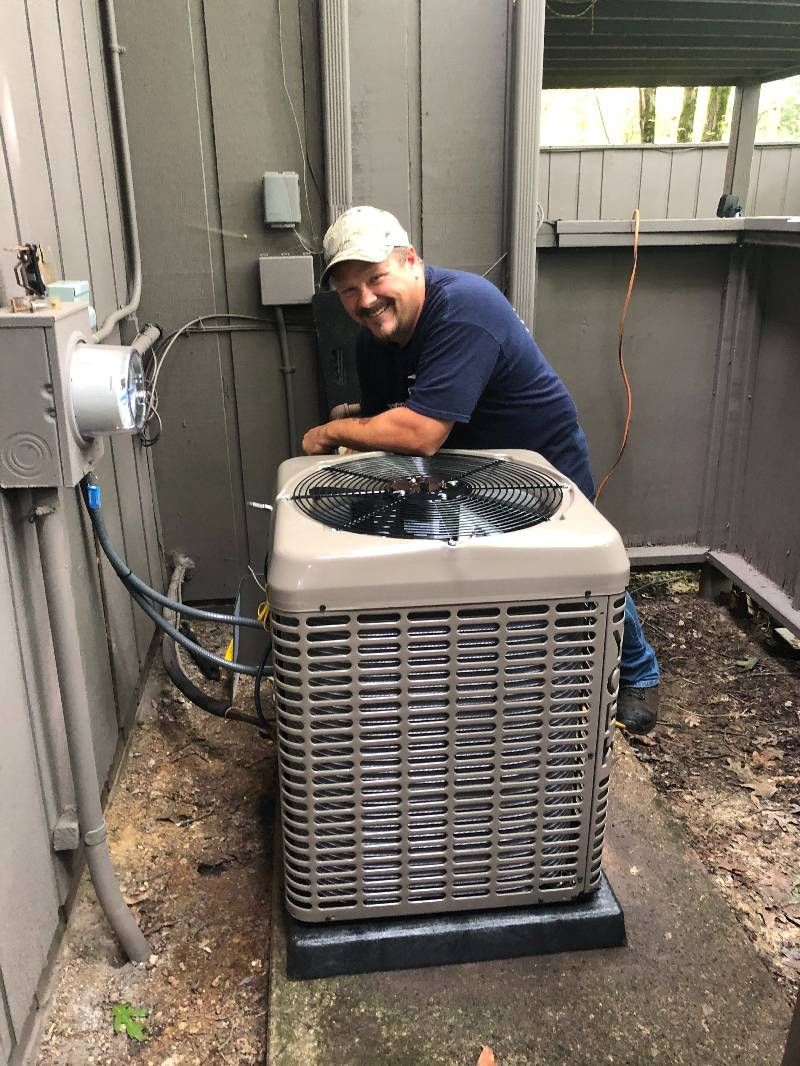 A man is working on an air conditioner outside of a building.