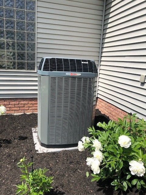 A large air conditioner is sitting on the side of a house.