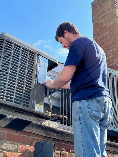 A man in a blue shirt is working on an air conditioner
