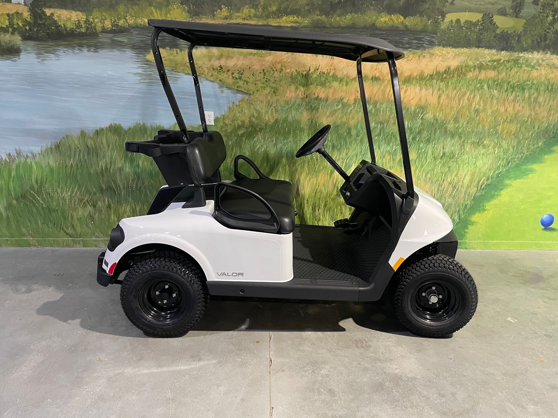 White golf cart with black canopy and wheels on a golf course.