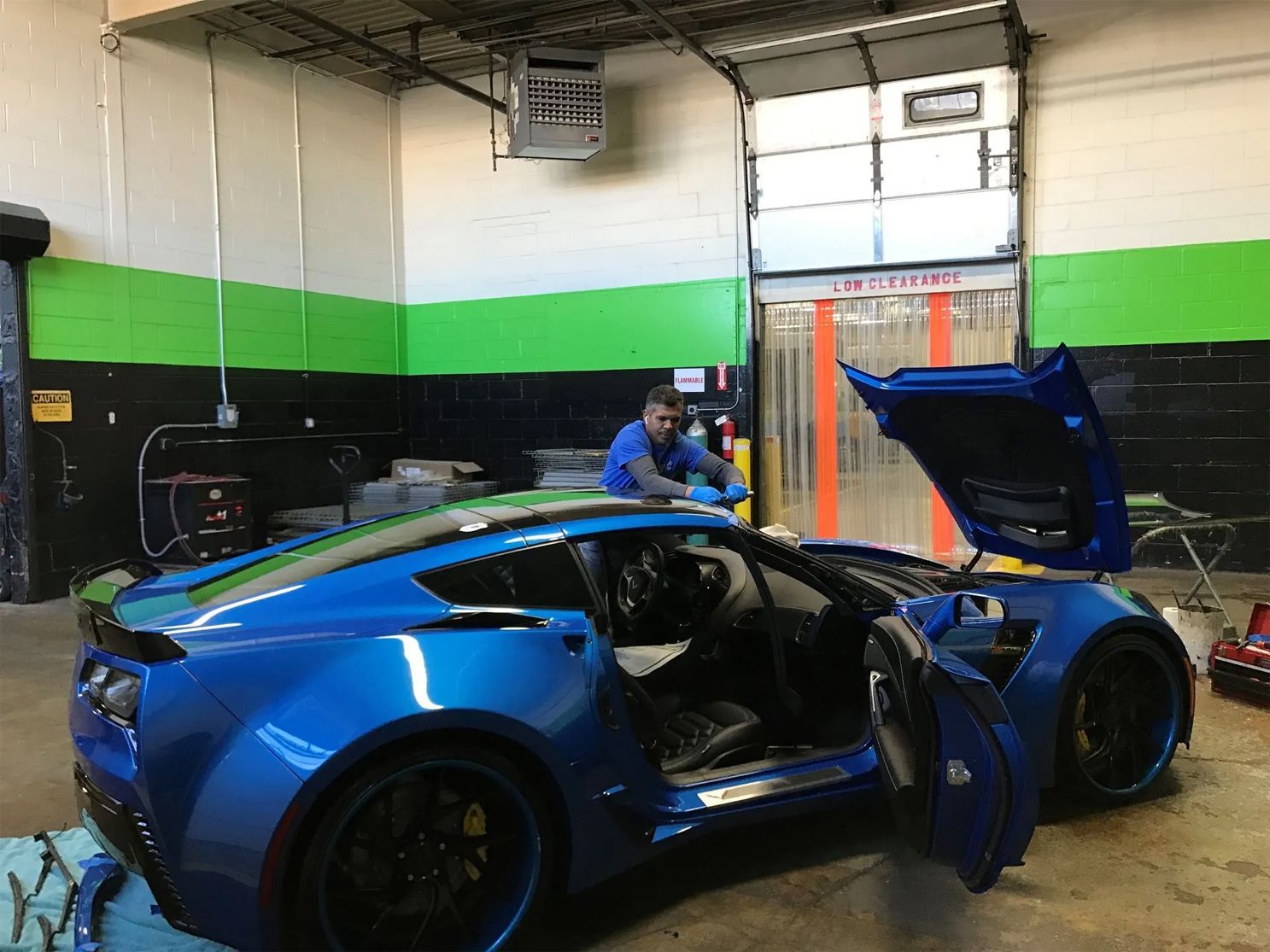 A man is working on a blue sports car in a garage