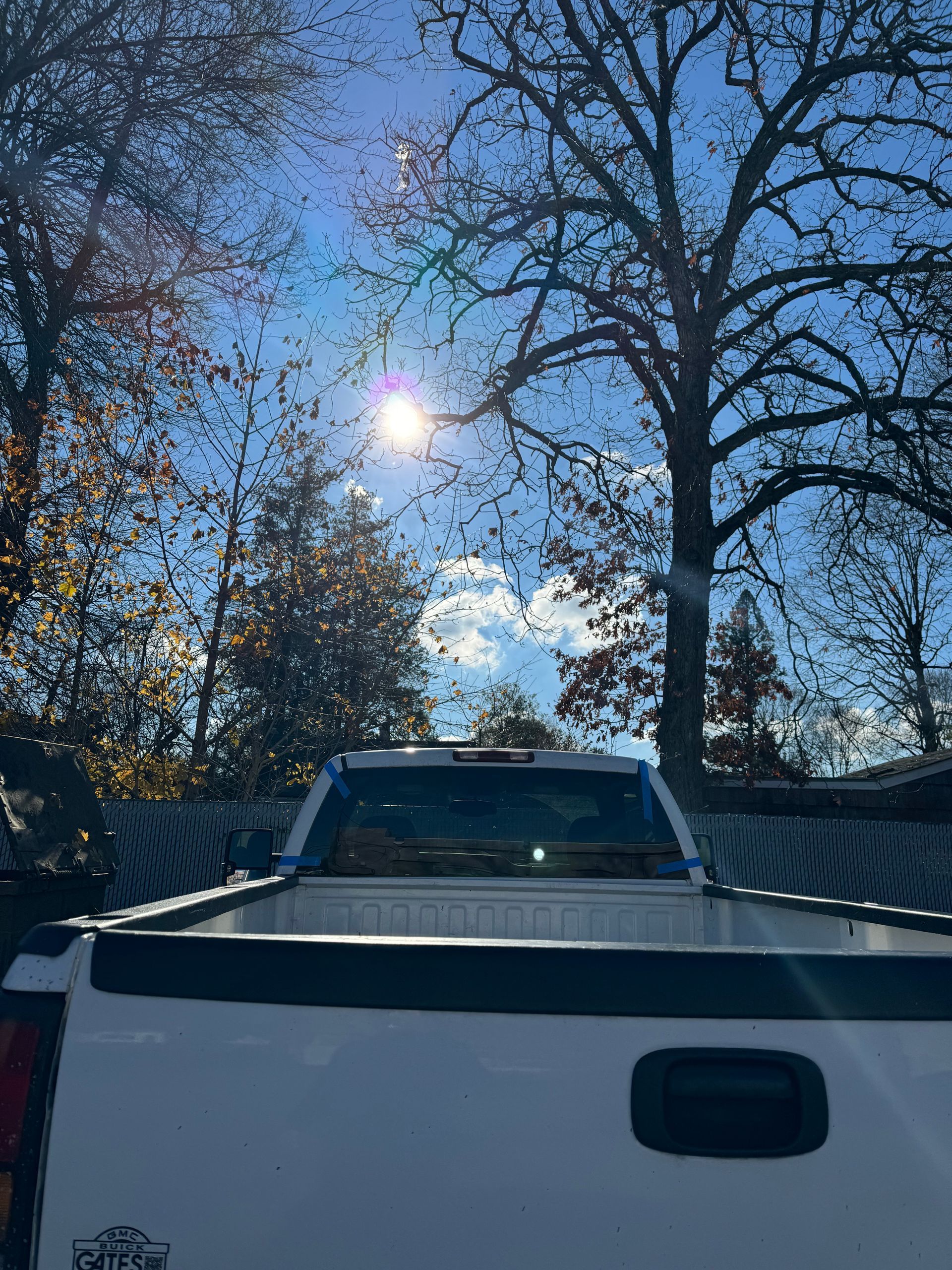 a white truck is parked in front of a tree with the sun shining through the trees