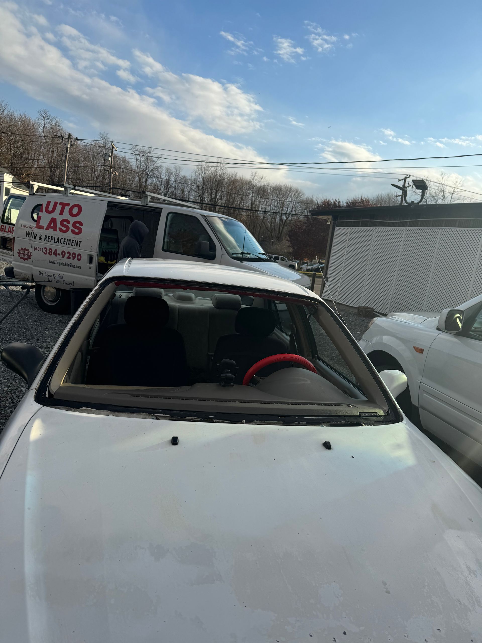 a white car with a broken windshield is parked beside a white van