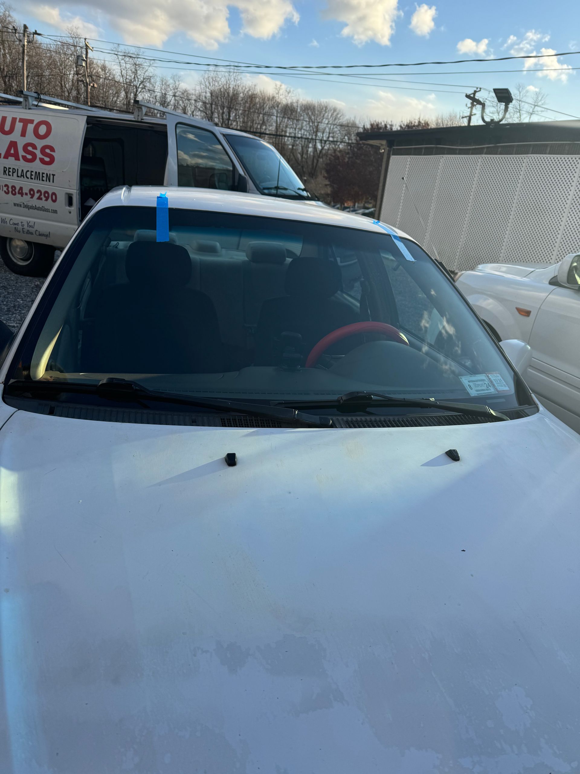a white car with a new windshield is parked in a parking lot