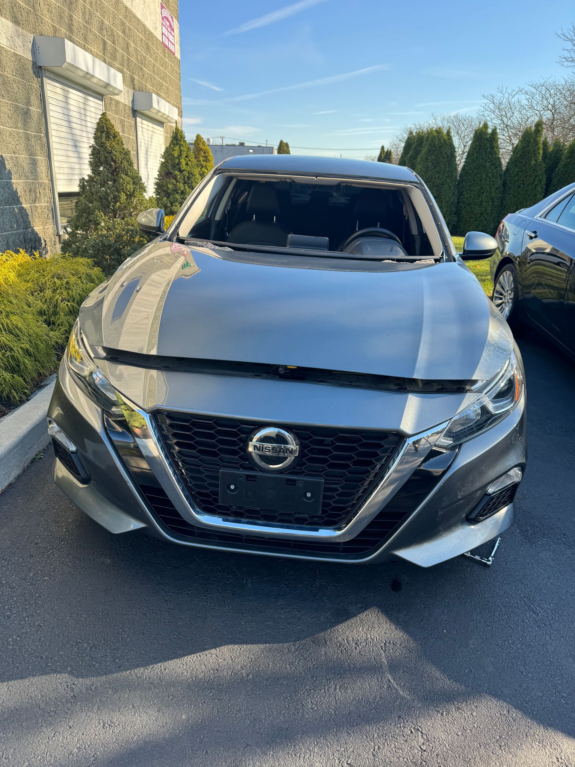 a silver Nissan Altima is parked in a parking lot