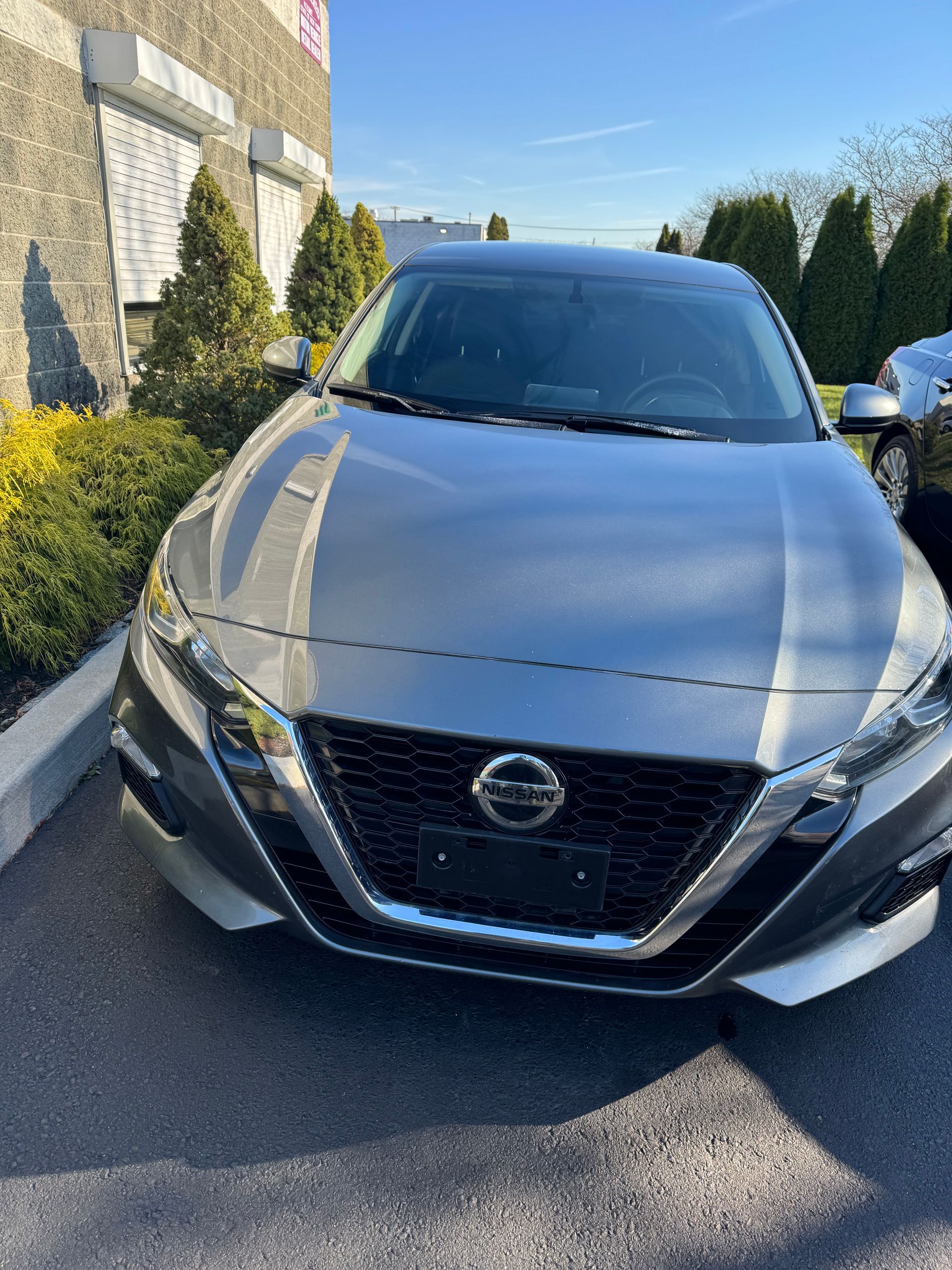 a silver Nissan Maxima is parked in front of a building