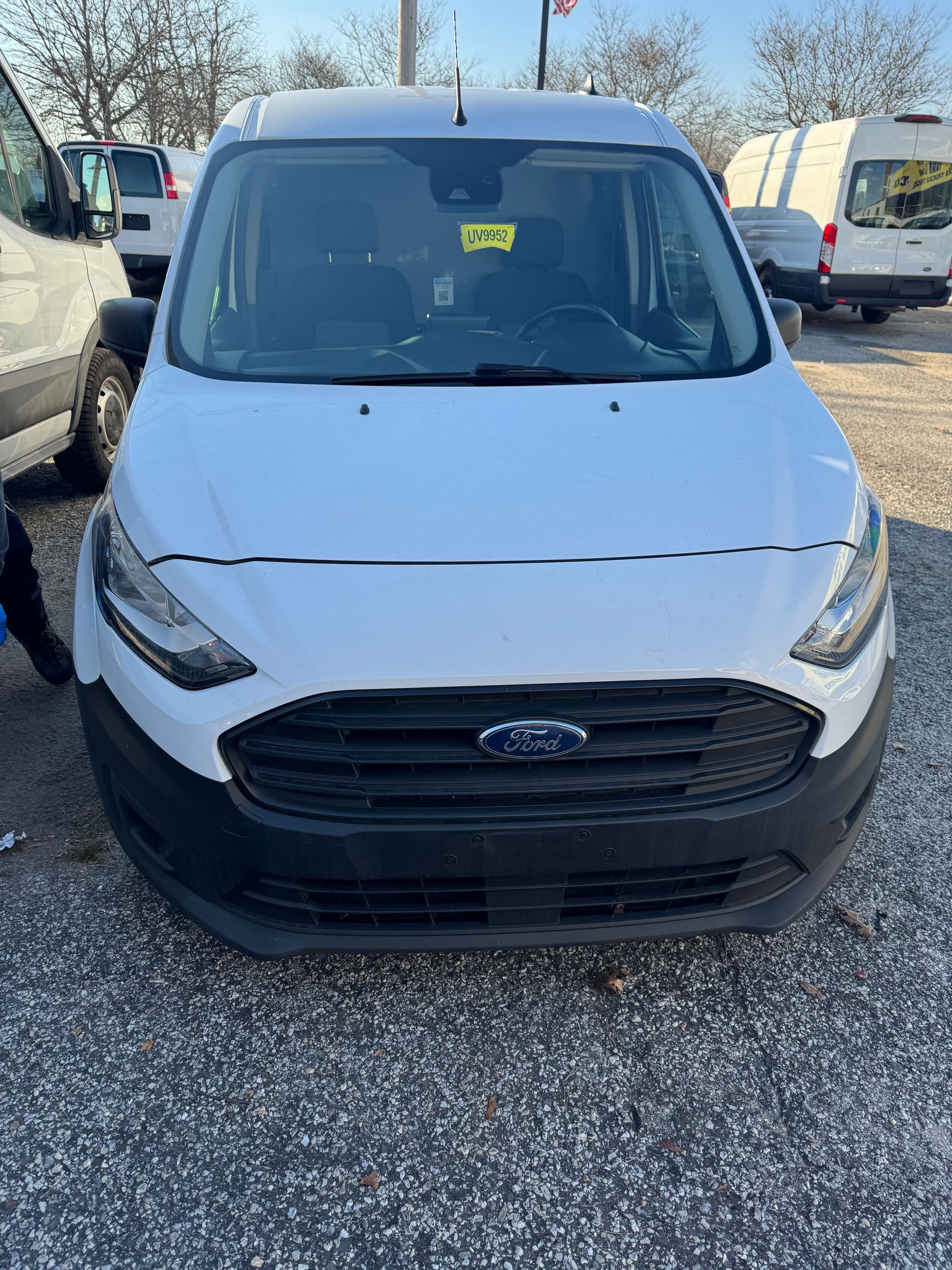 a white Ford Transit Connect van is parked in a gravel lot