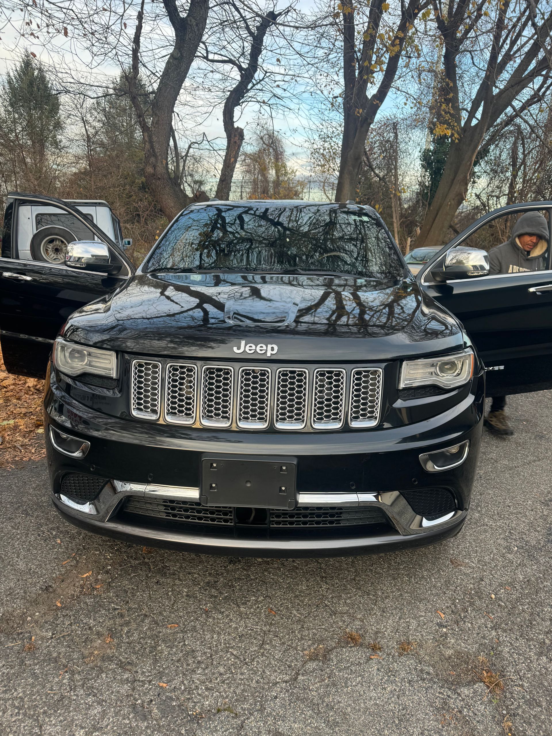 a black Jeep Grand Cherokee is parked on the side of the road with its doors open