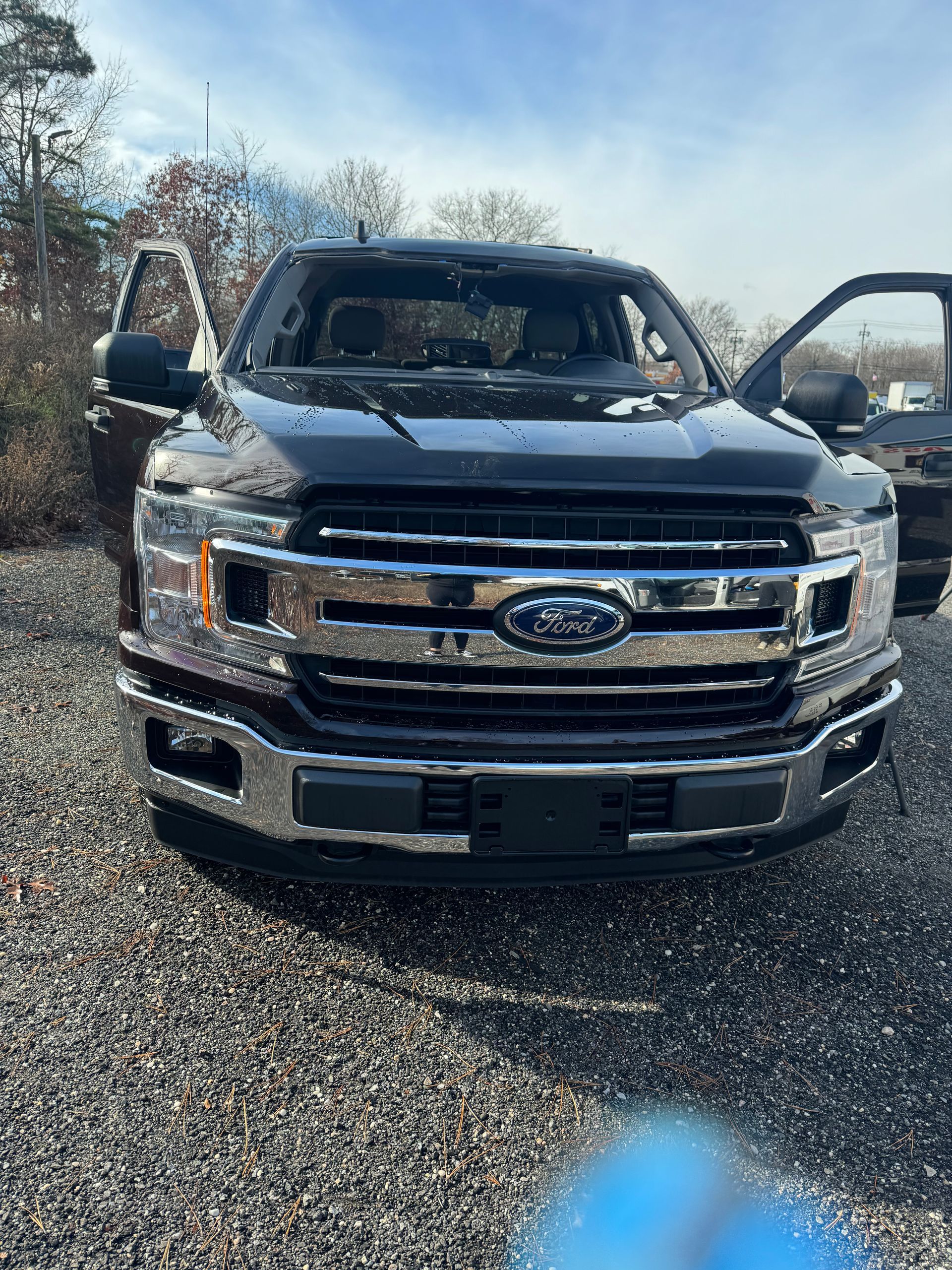 a black Ford F150 is parked in a gravel lot