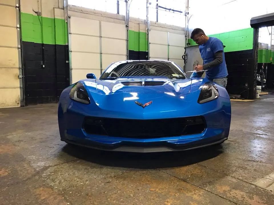 A man is working on a blue sports car in a garage