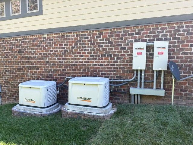 Two outdoor HVAC units and electrical boxes mounted on a brick house wall