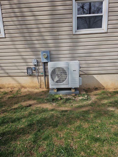 Outdoor HVAC unit beside a beige house wall with utility meters and grass in front