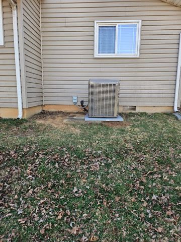 Backyard exterior wall with window and central air unit on a small concrete pad