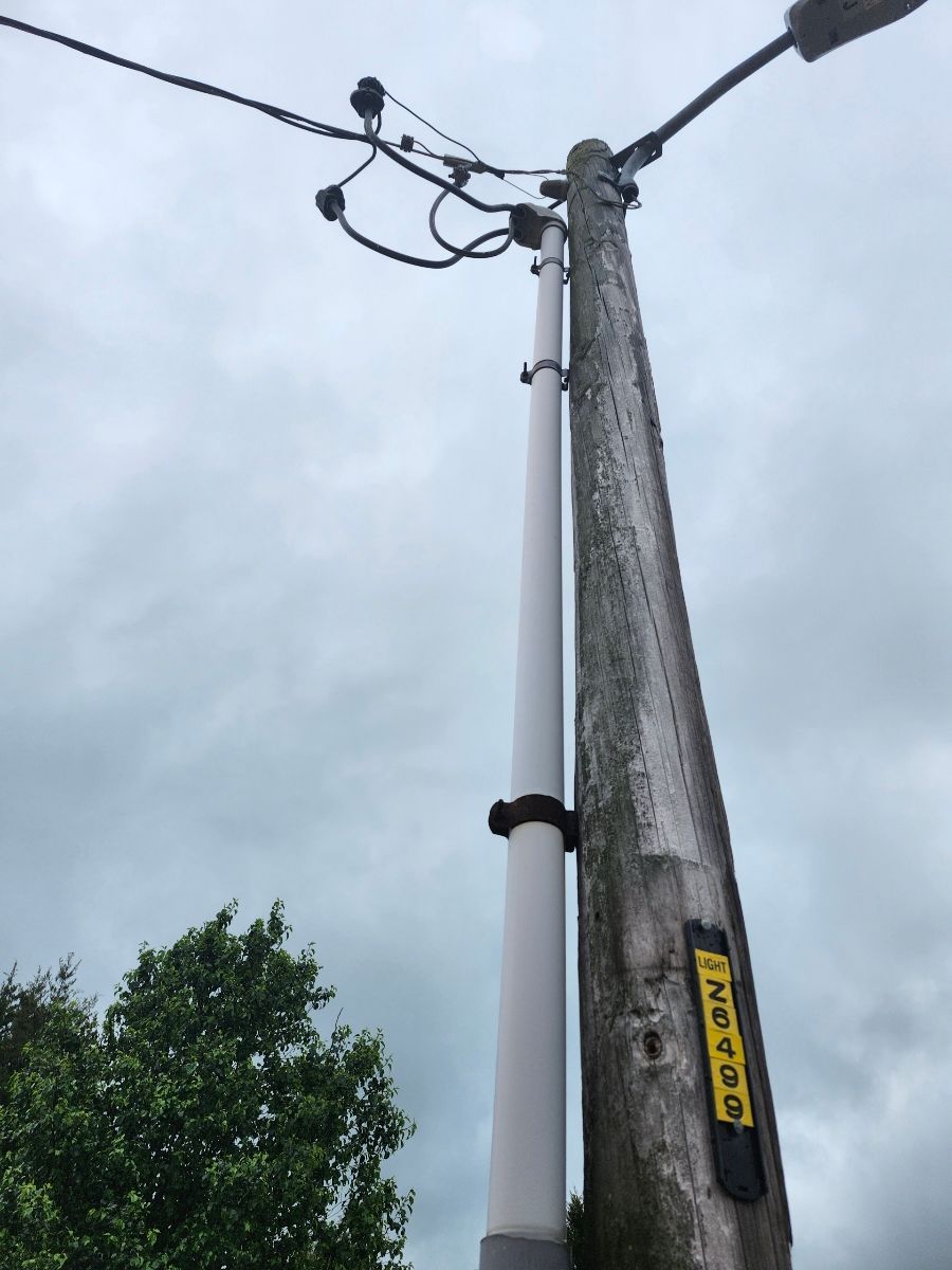Utility pole with attached cables and streetlight against a cloudy sky