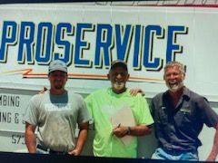 Three men standing in front of a ProService sign, smiling outdoors.