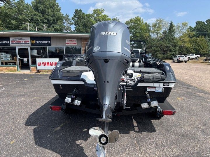 Rear view of a black speedboat with a large Yamaha outboard motor in a parking lot.