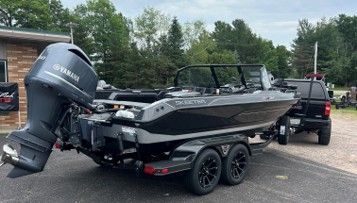 Black Yamaha fishing boat on a trailer parked in a lot, with a pickup truck behind it.