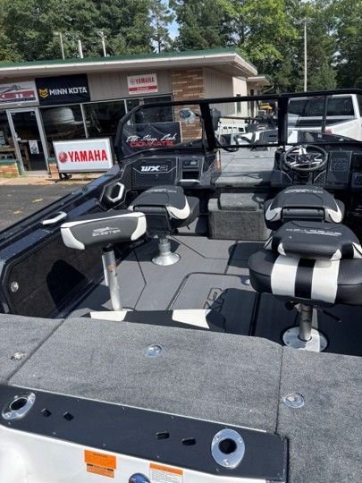 Bass boat with two seats parked outside a Yamaha marine dealership.