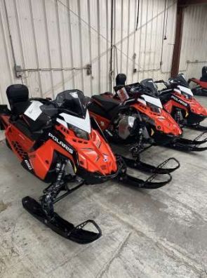 Black and orange Ski-Doo snowmobile parked indoors, angled shot.