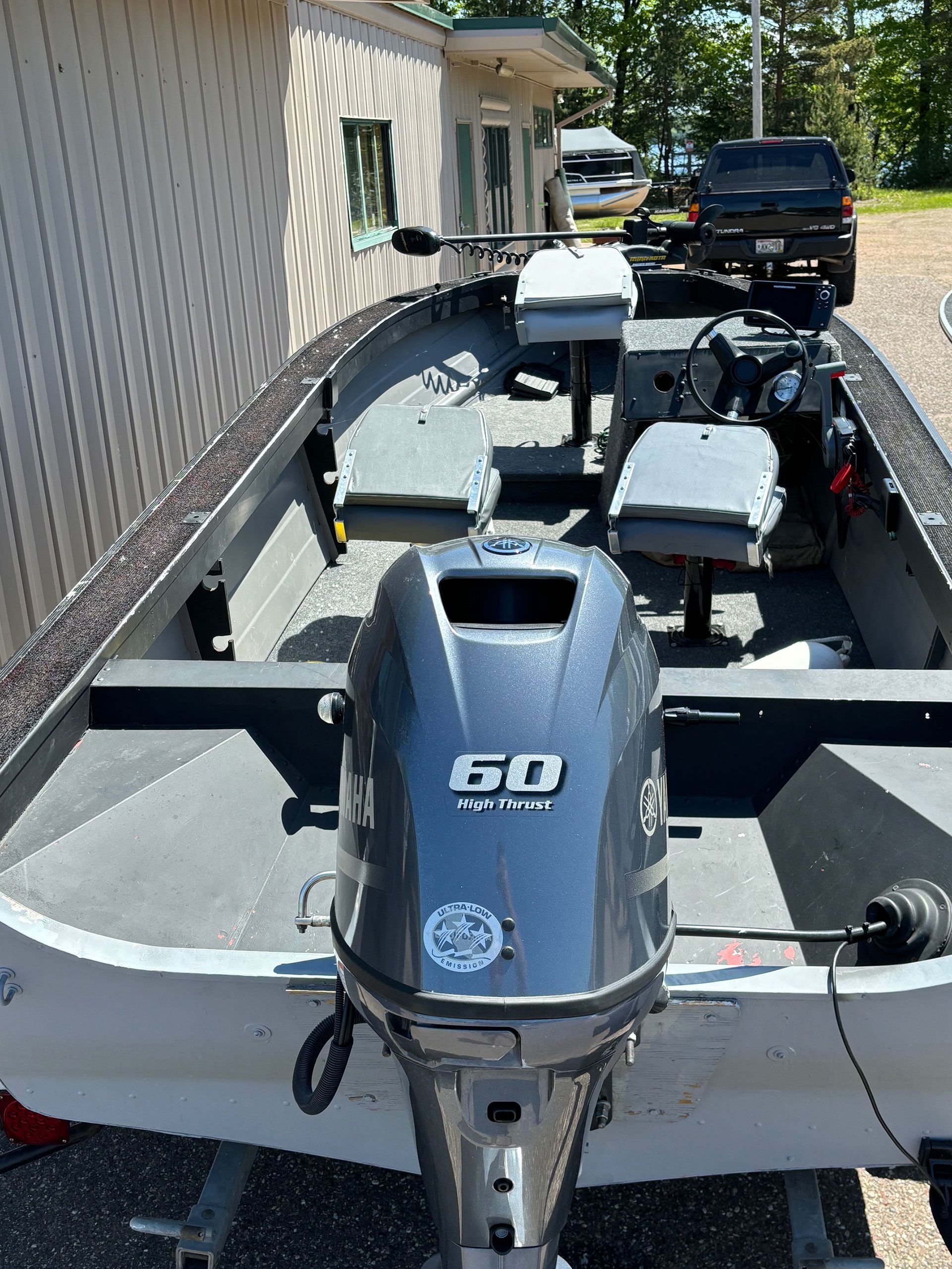 A boat with a 60 hp outboard motor is parked in front of a building