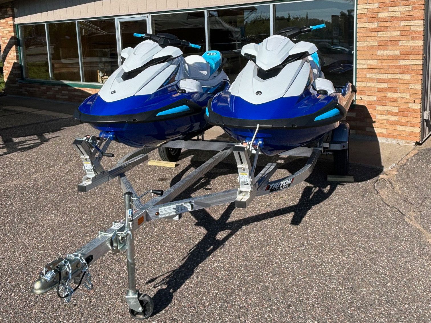 Two jet skis are parked on a trailer in front of a building