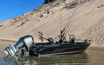 A boat is sitting in the water near a sand dune