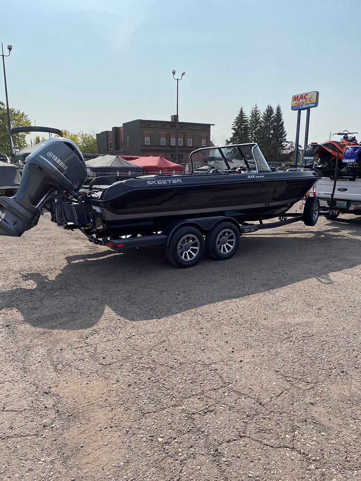 A boat is being towed by a trailer in a parking lot
