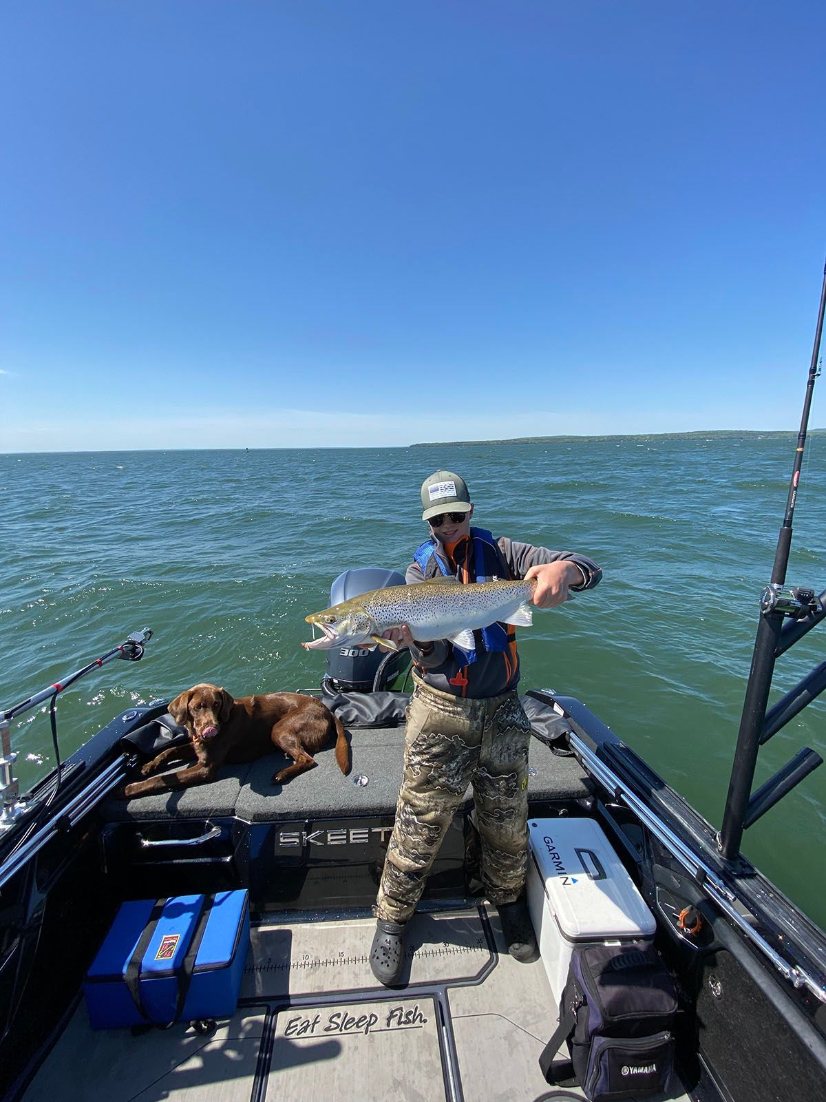 A boy is standing on a boat holding a large fish
