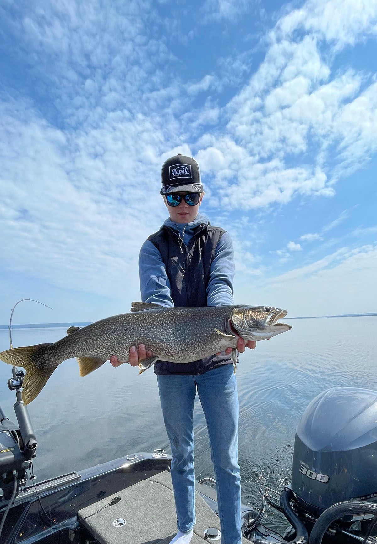 A boy is standing on a boat holding a trout