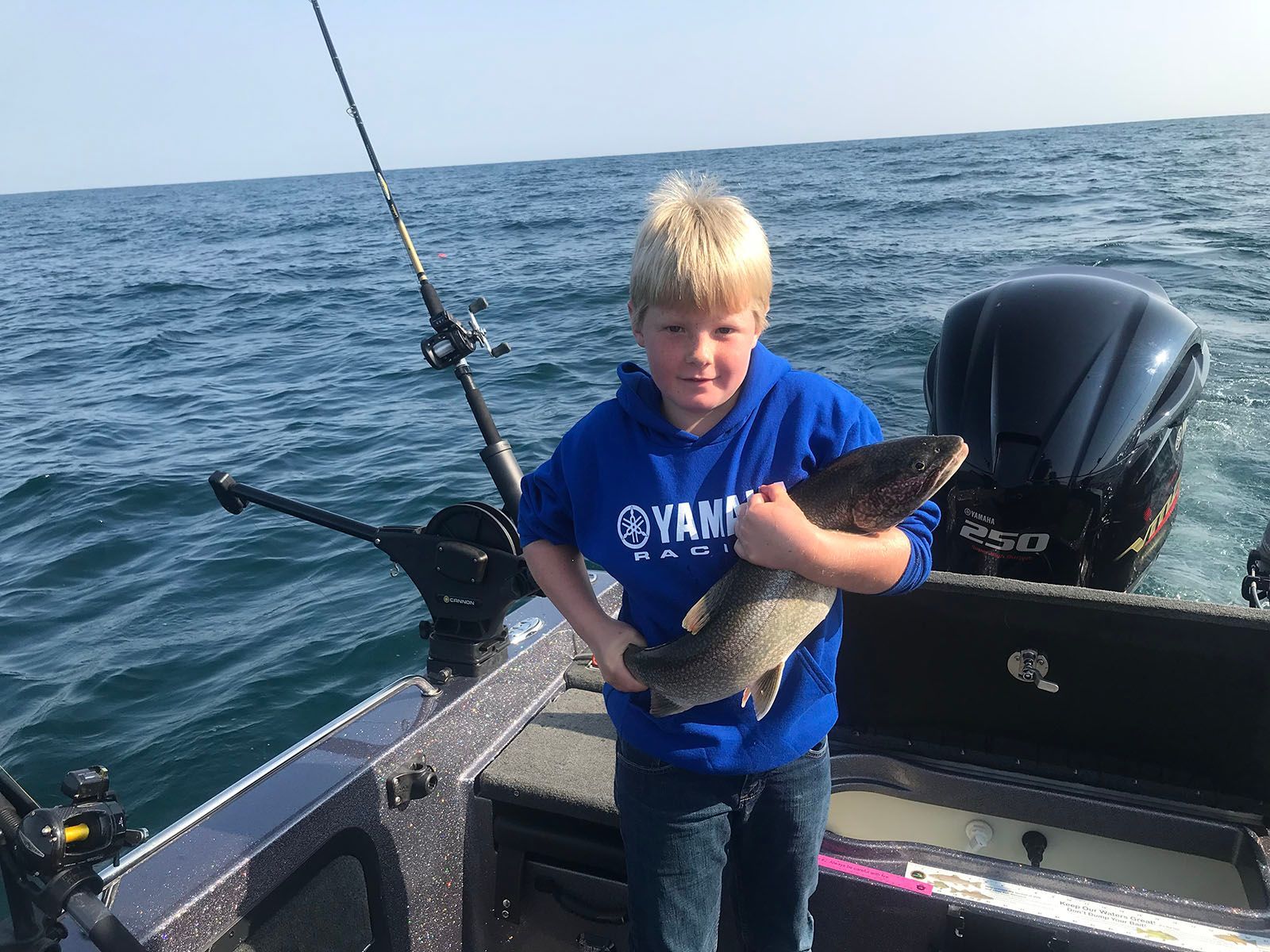 A young boy is holding a fish on a boat