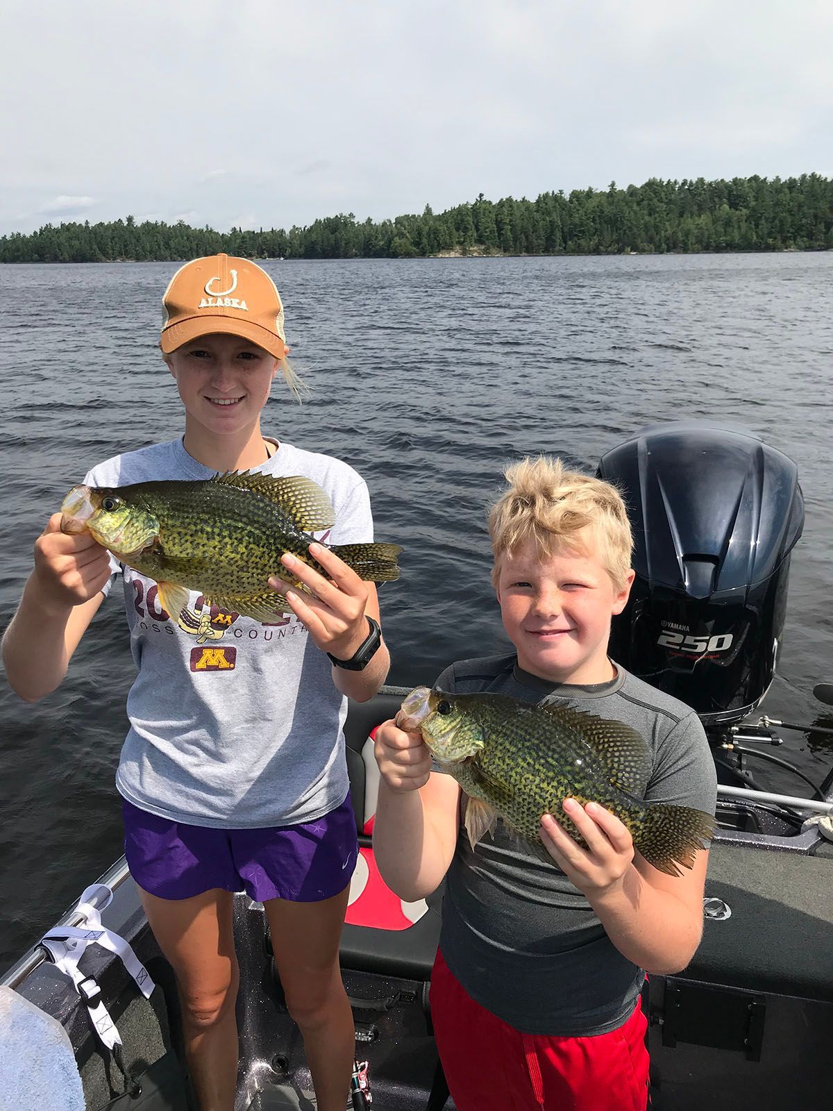 A boy and a girl are holding fish on a boat