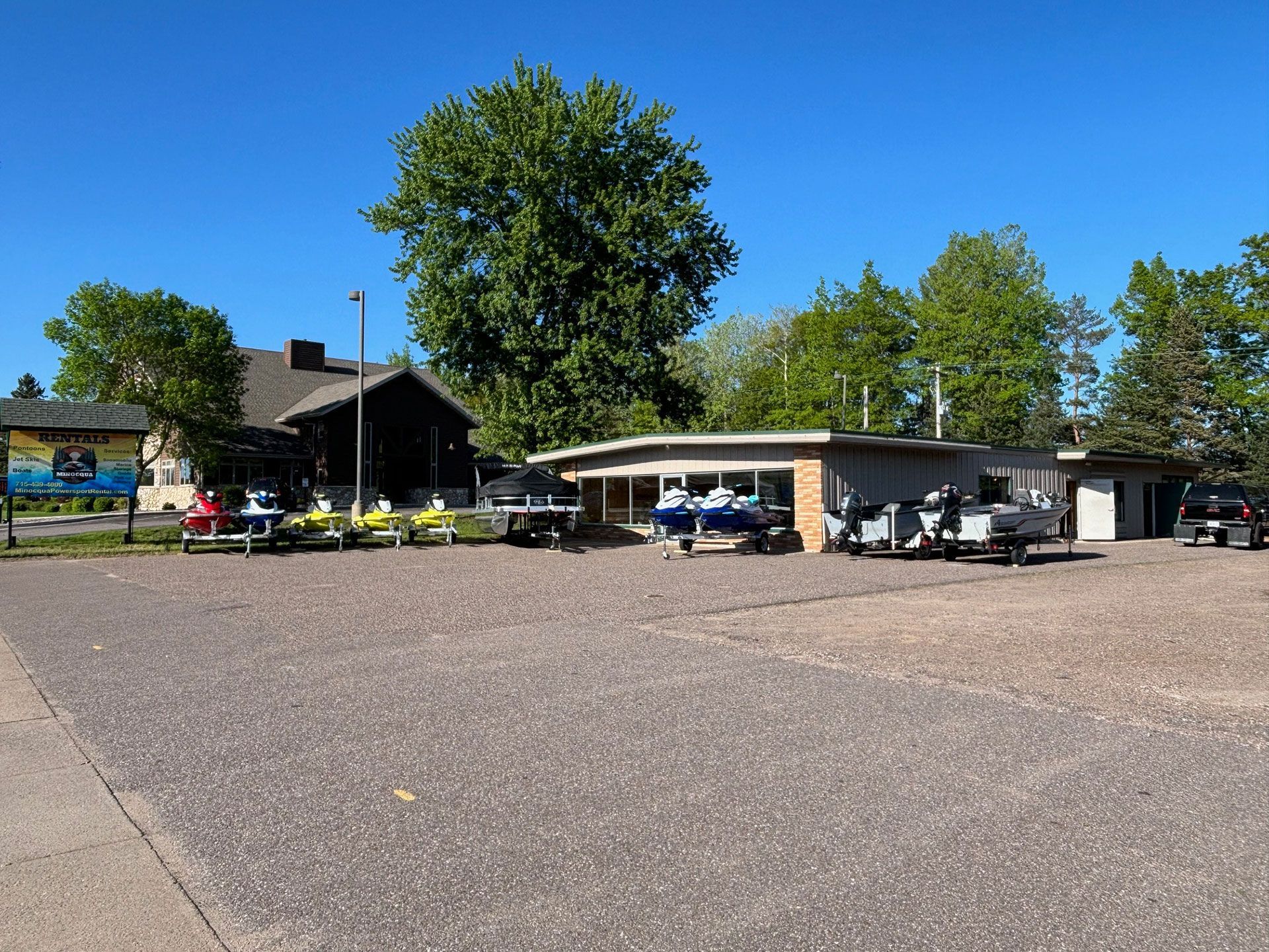 A row of fishing boat and jet skis are parked in front of a building