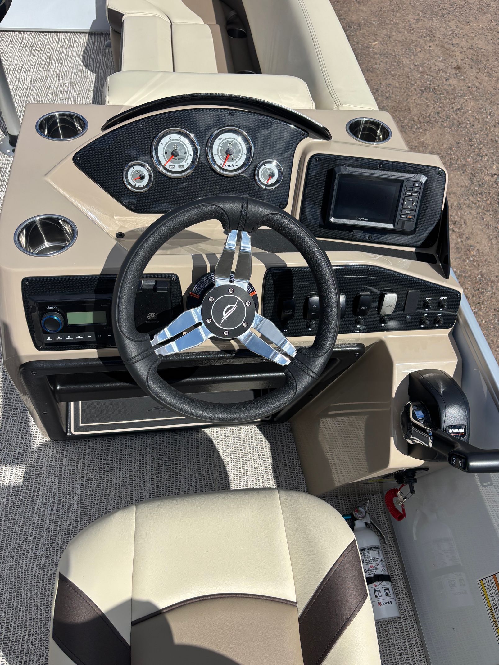 Luxury boat helm with beige seats, black steering wheel, gauges, and a touchscreen display